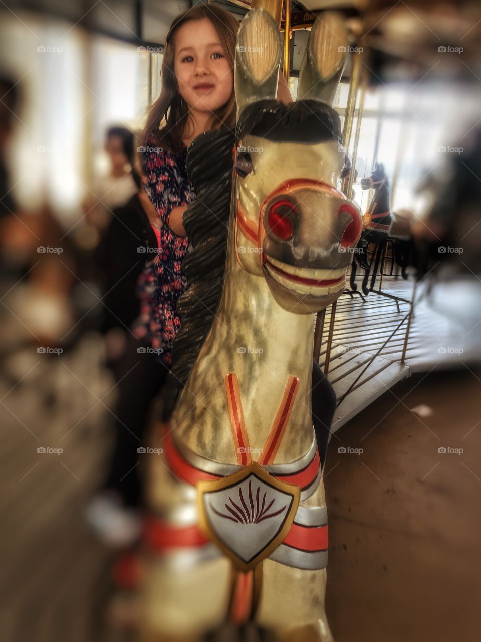 Small girl enjoying carousel horse ride
