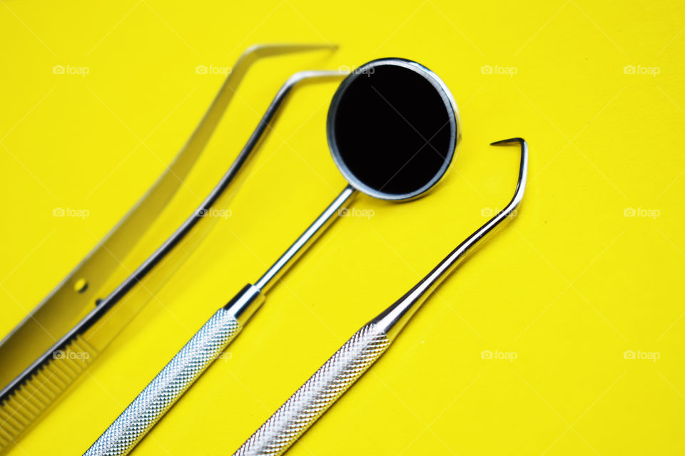 Tools for dental treatment on a yellow background.