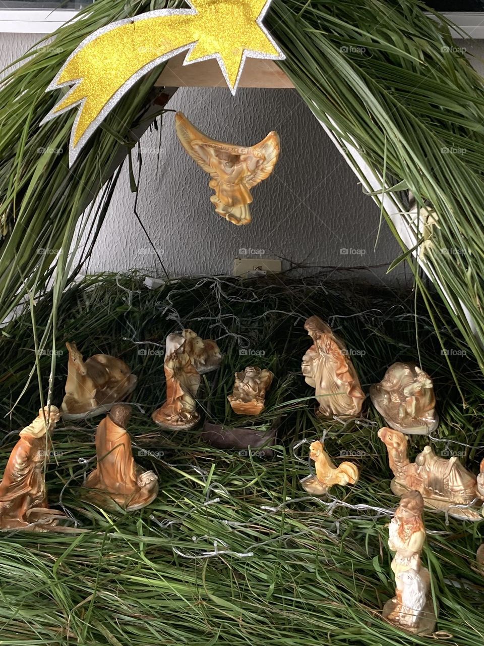 Presépio natalino com personagens confeccionado com gesso. Presépio feito com madeira e folhas de palmeira.