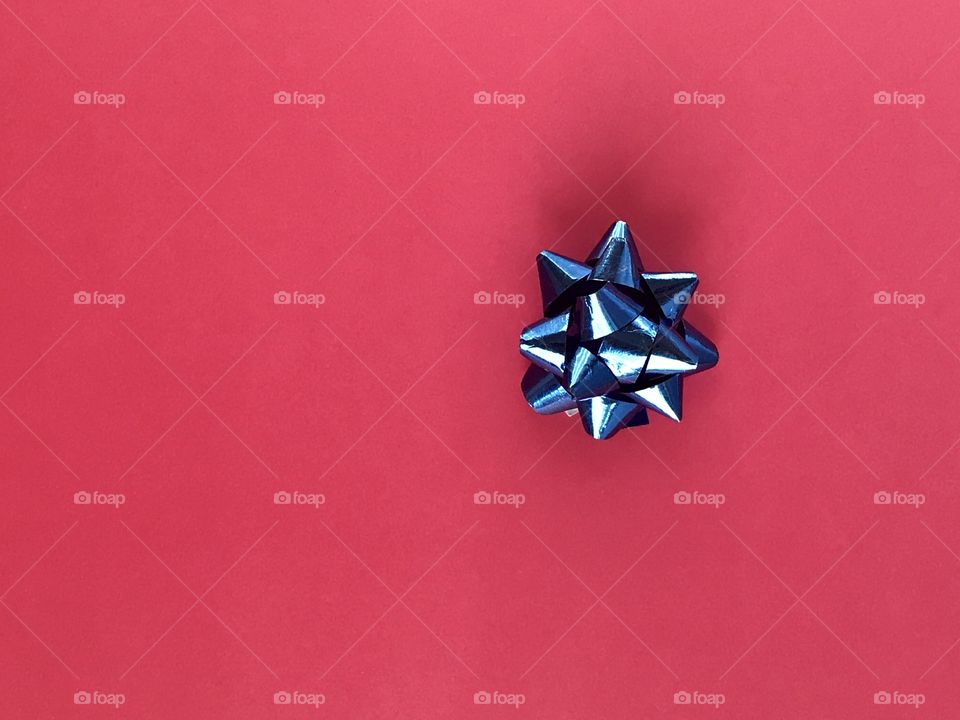 A shiny blue bow on a pink background 