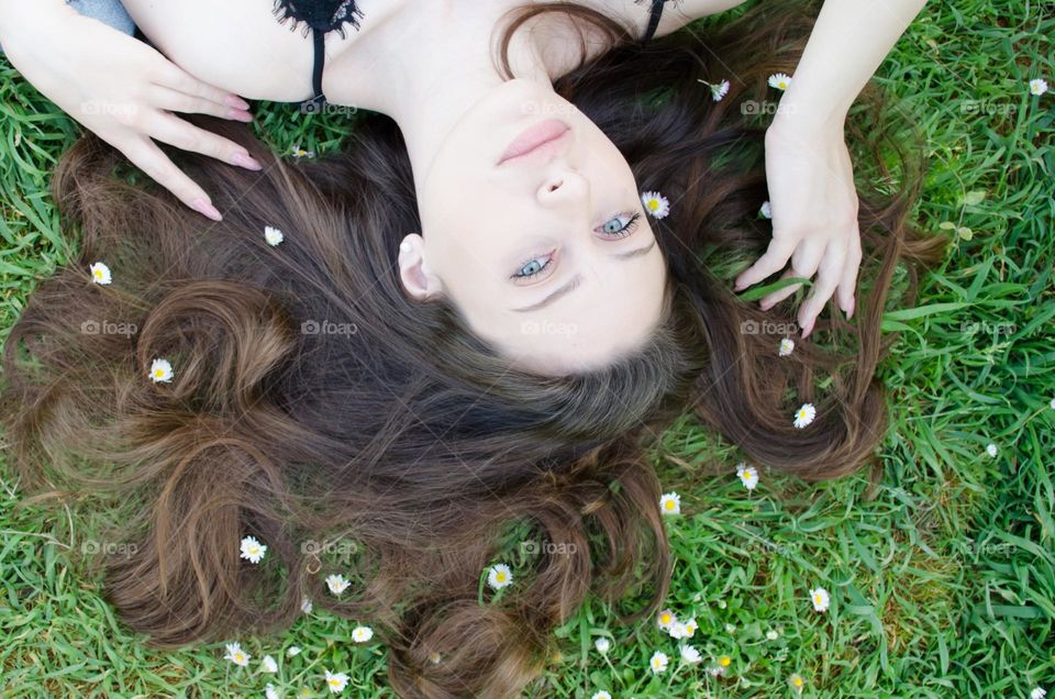 Portrait of Beautiful Young Girl on Background of Daisies