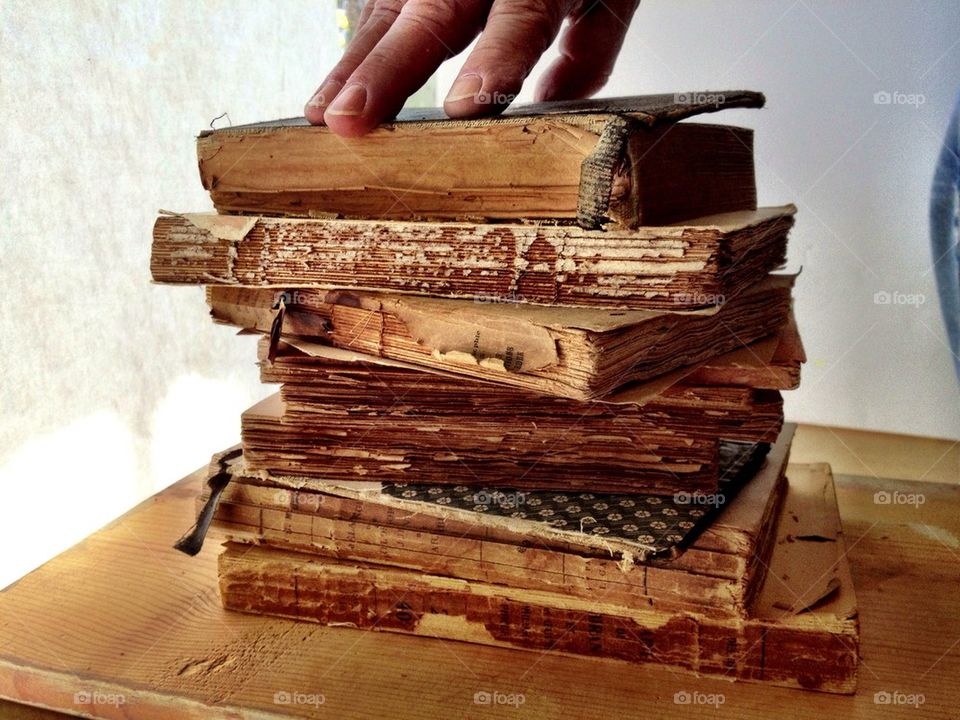 Man's fingers atop stack of damaged books