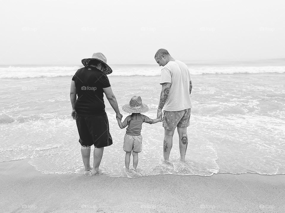 Standing in the ocean holding hands, black and white family portrait, family holding hands, loving family portrait 