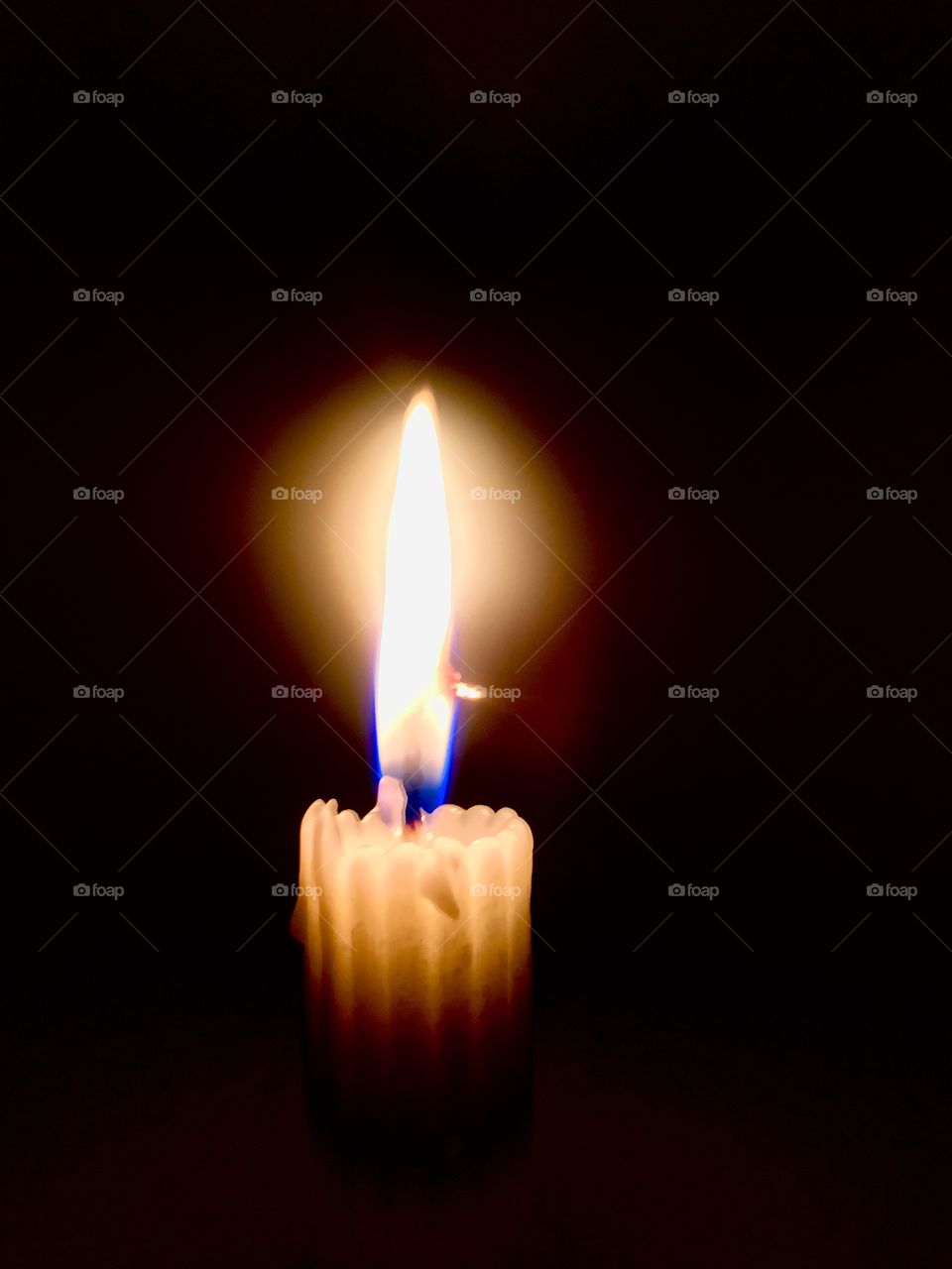 Candle surrounded with darkness and a bright light with attractive flame