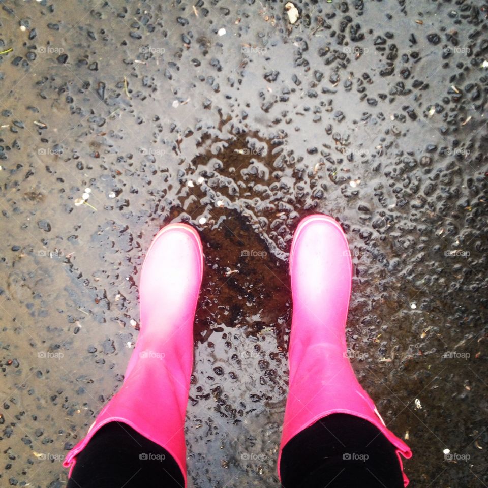 Splashing in the rain. Pink rain opts on pavement