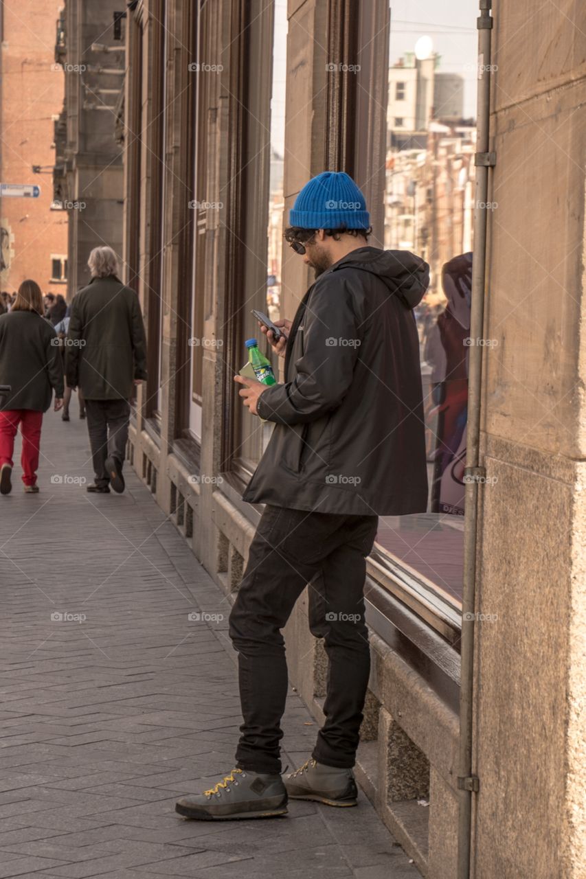 A guy standing on the sidewalk checking his phone