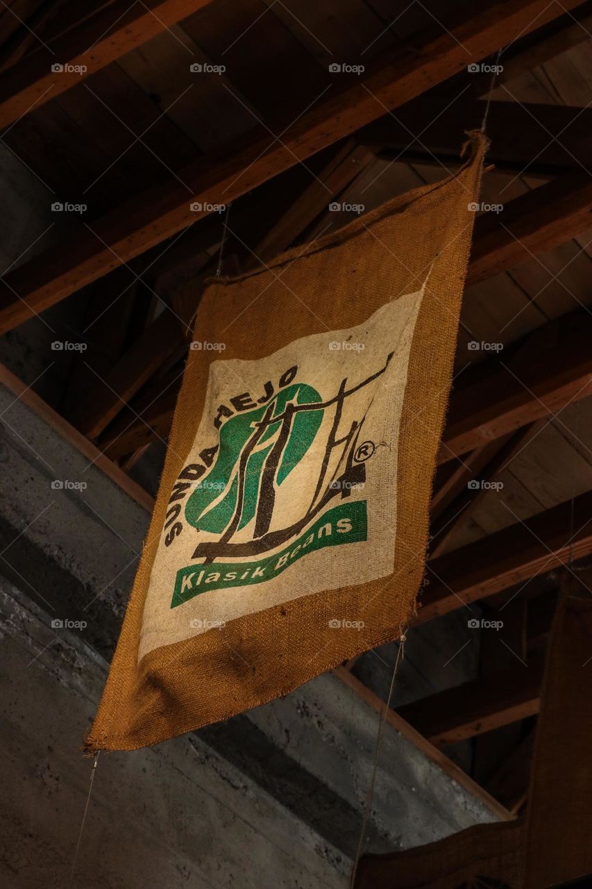 Various coffee bean sacks used as decor in a coffee shop with exposed wood beams on the ceiling 
