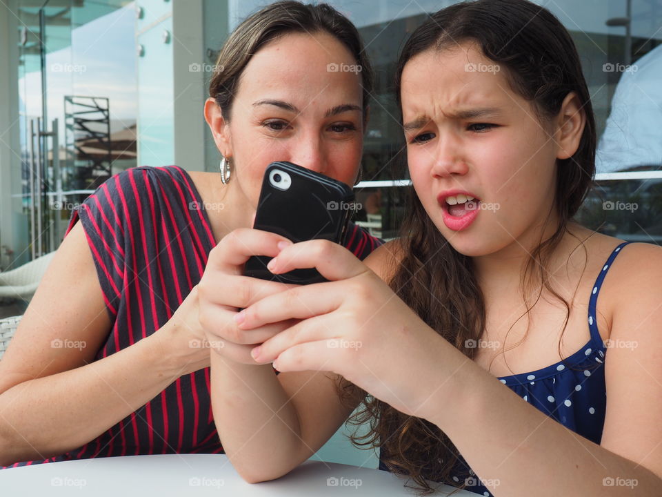 Mother and daughter chatting. Mother and daughter spending fun time while chatting on smartphone