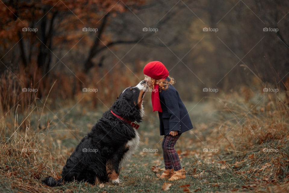 Little girl with dog in autumn park 