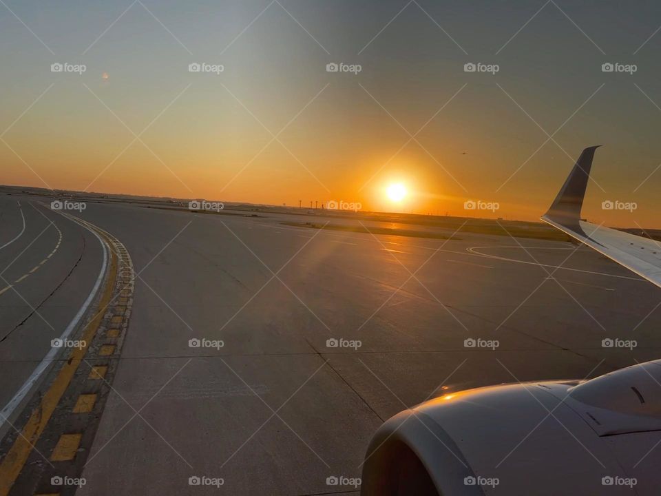 Sun setting in the horizon during a flight landing at airport landing strip 