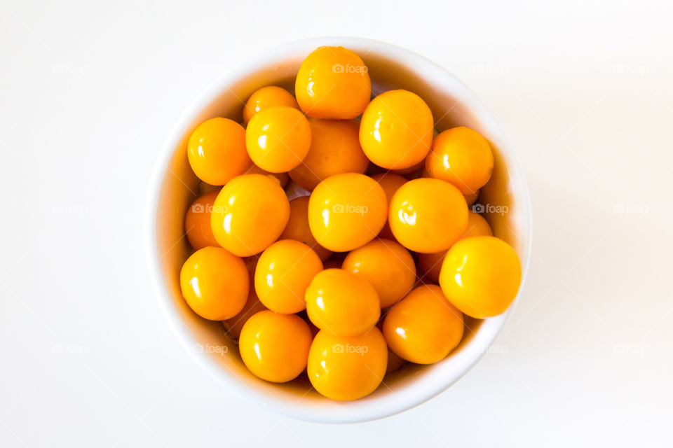 Delicious fresh and healthy - my kind of meal! Yellow fresh gooseberries in white bowl on a white table.