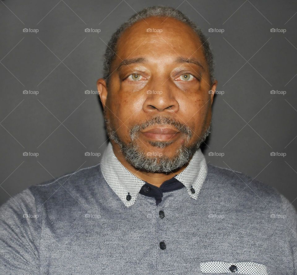 portrait of a man in a collared shirt with green eyes.