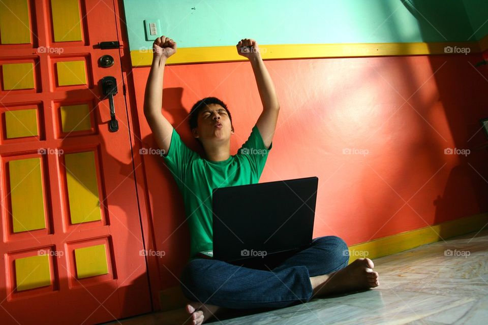 young asian teen with a laptop computer in a living room