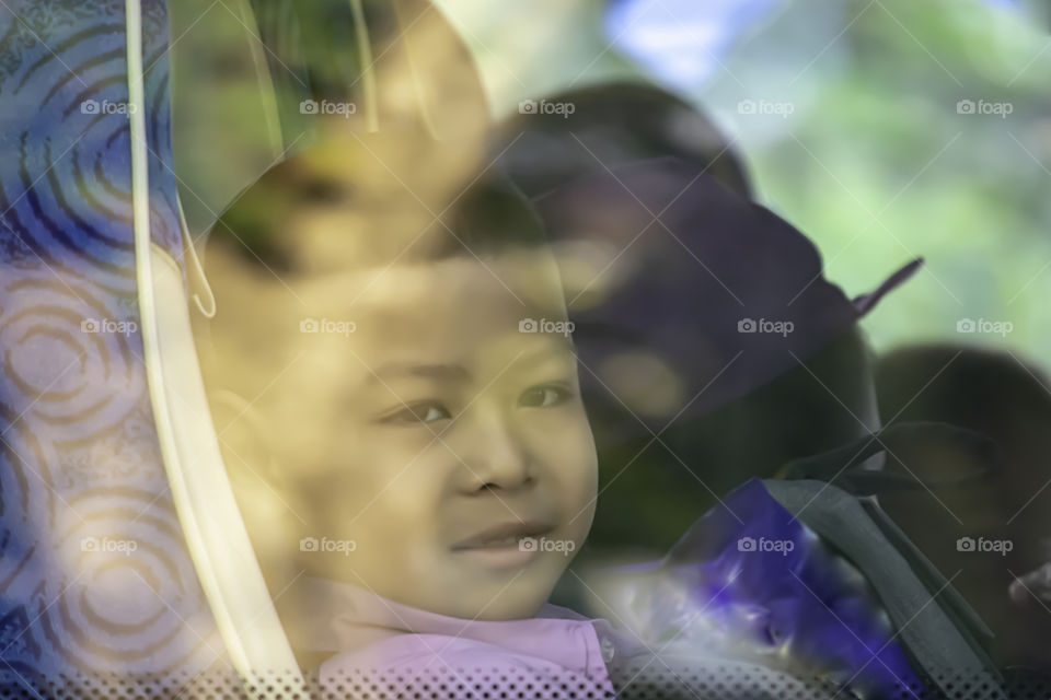 Asian boy sitting on a school bus.