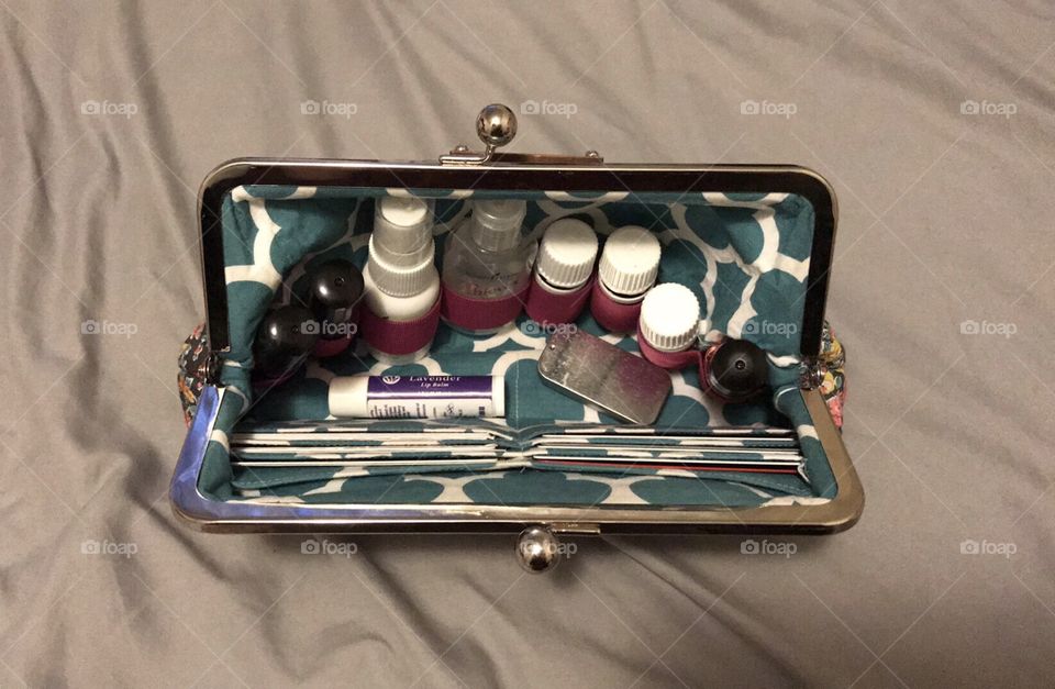 A lovely, perfectly organized, classic clutch with a silver lobster clasp and a modern white and teal print. It contains bottles, spray, lip balm, a tin, and cards.