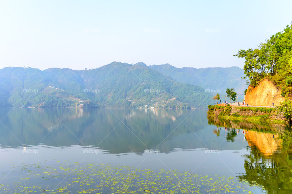 Photograph of autumn colourful lake, mountain, clear sky with reflexation in water. Wide angle landscape of Pokhara Lake at Kathmandu Nepal. Vintage film look. Vacation Freedom, Simplicity Concept.