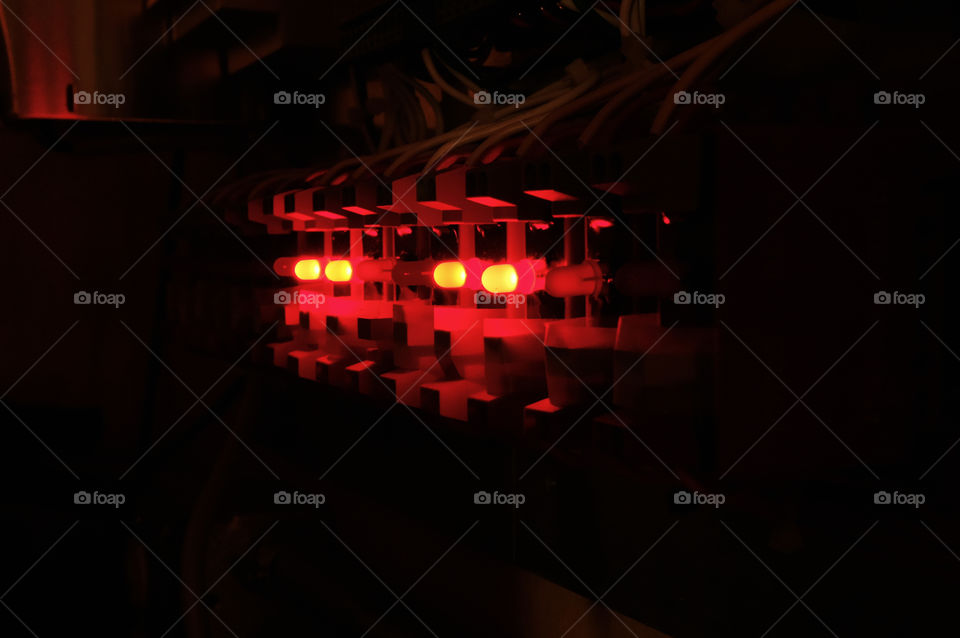 View in the dark of a row of solid state relays with red LED lights used for data acquisition and control systems. 