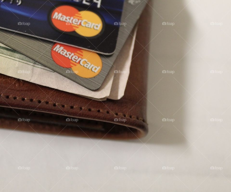 Close up of credits cards and some dollar bills on a leather wallet.