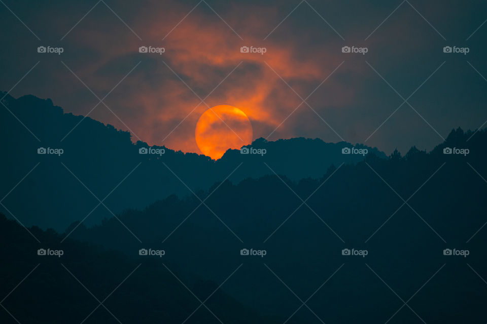 Beautiful sun being covered by layers of hills