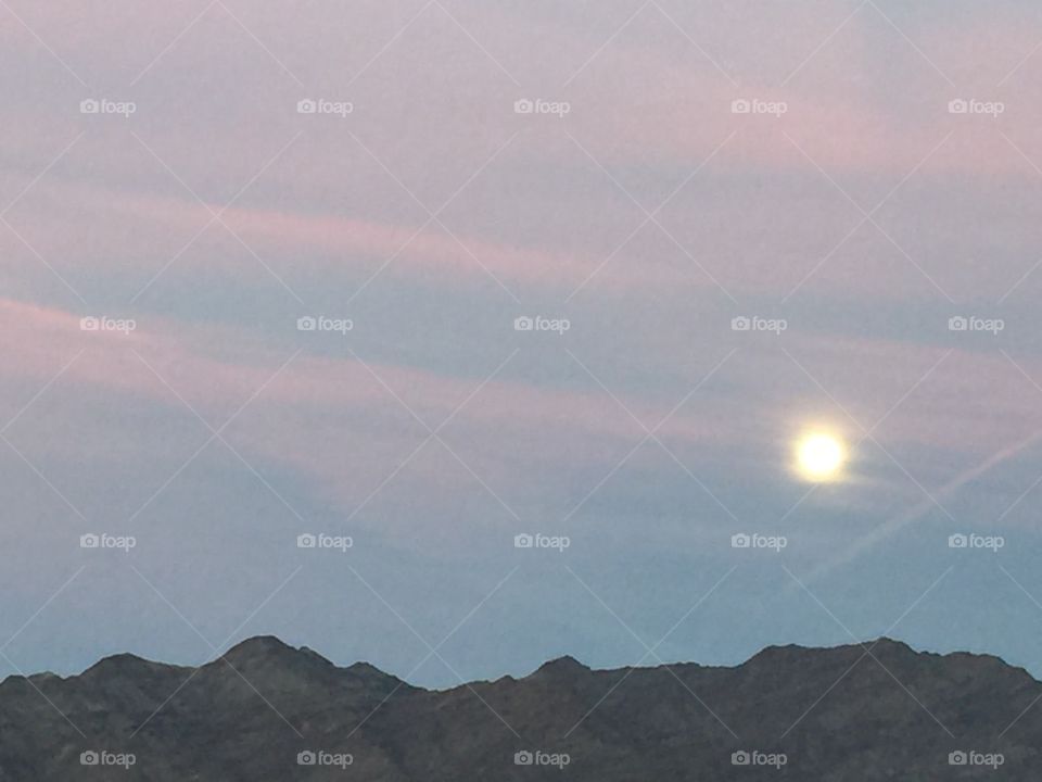 Full moon setting over the western desert mountains in the predawn morning. 