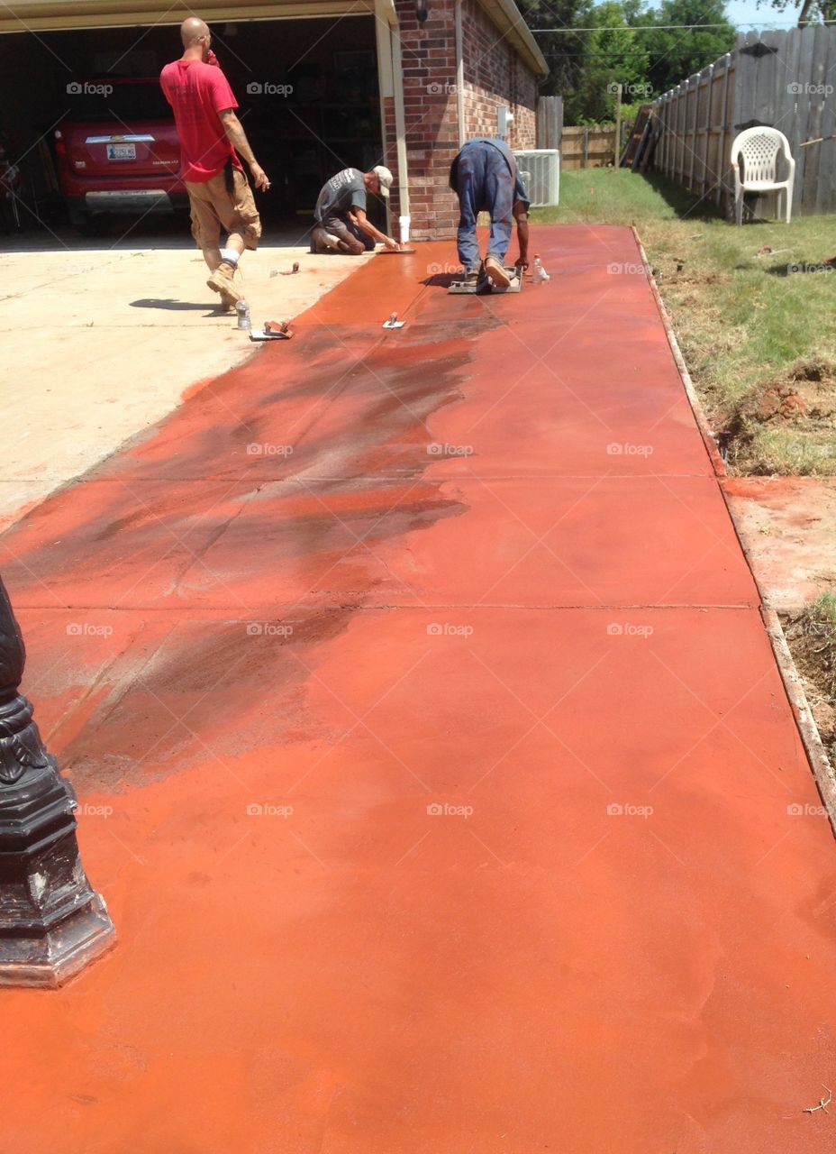 Men at work laying concrete and adding terra cotta and black color.