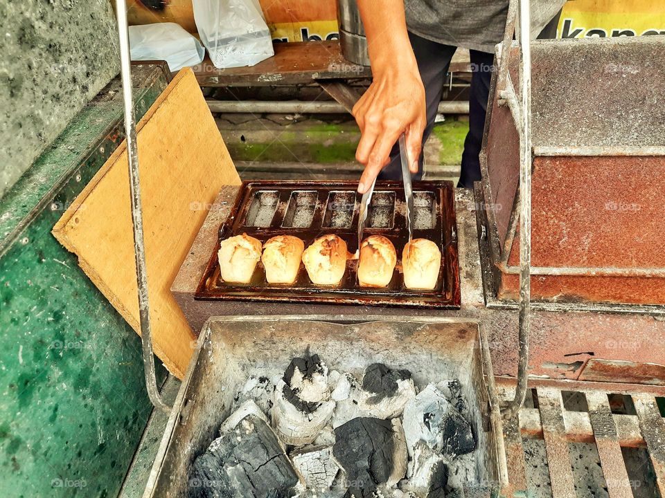 hands in frame. Loave of cake, traditional food cooked using charcoal