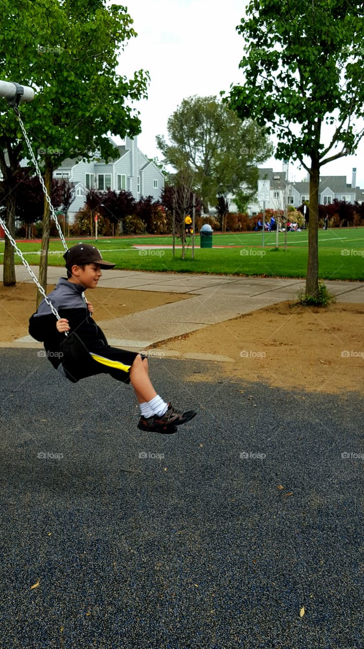 Boy playing on swing in park