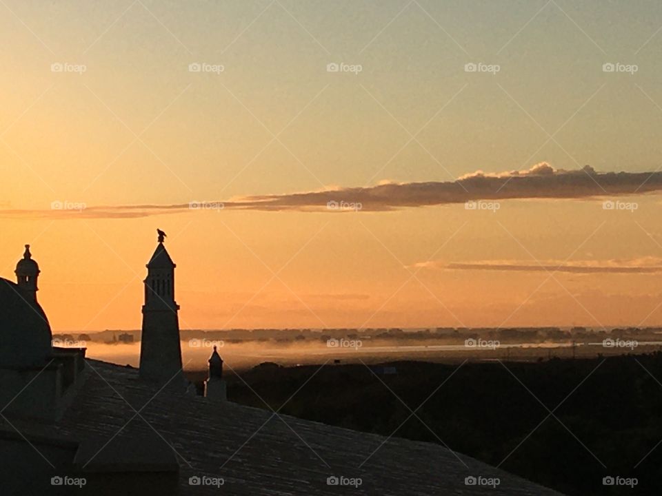 Rising sun above mist and chimneys 
