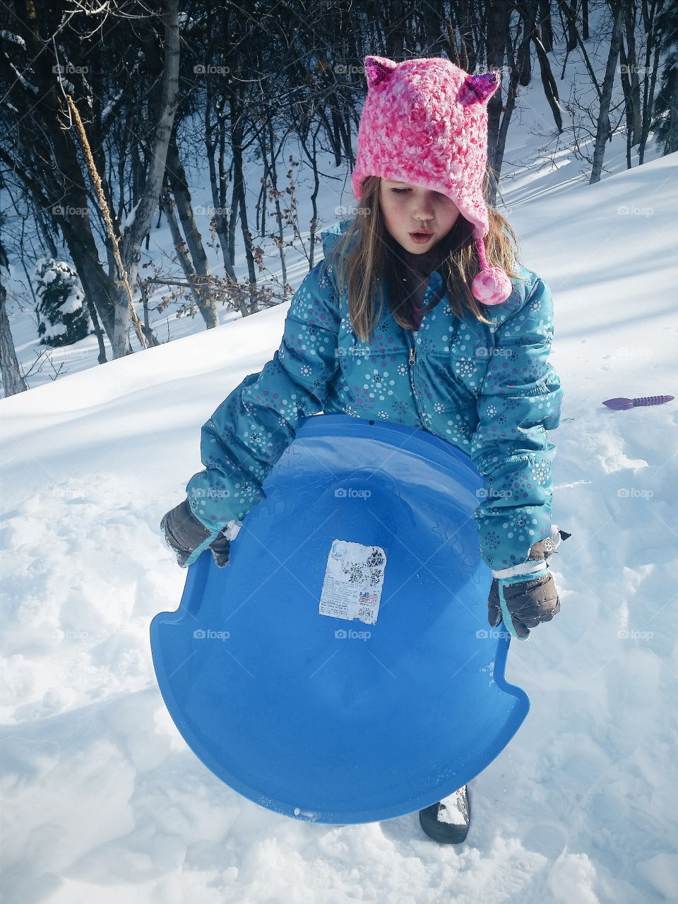 Girl holding a sled. Young white girl holding a blue sled in the snow