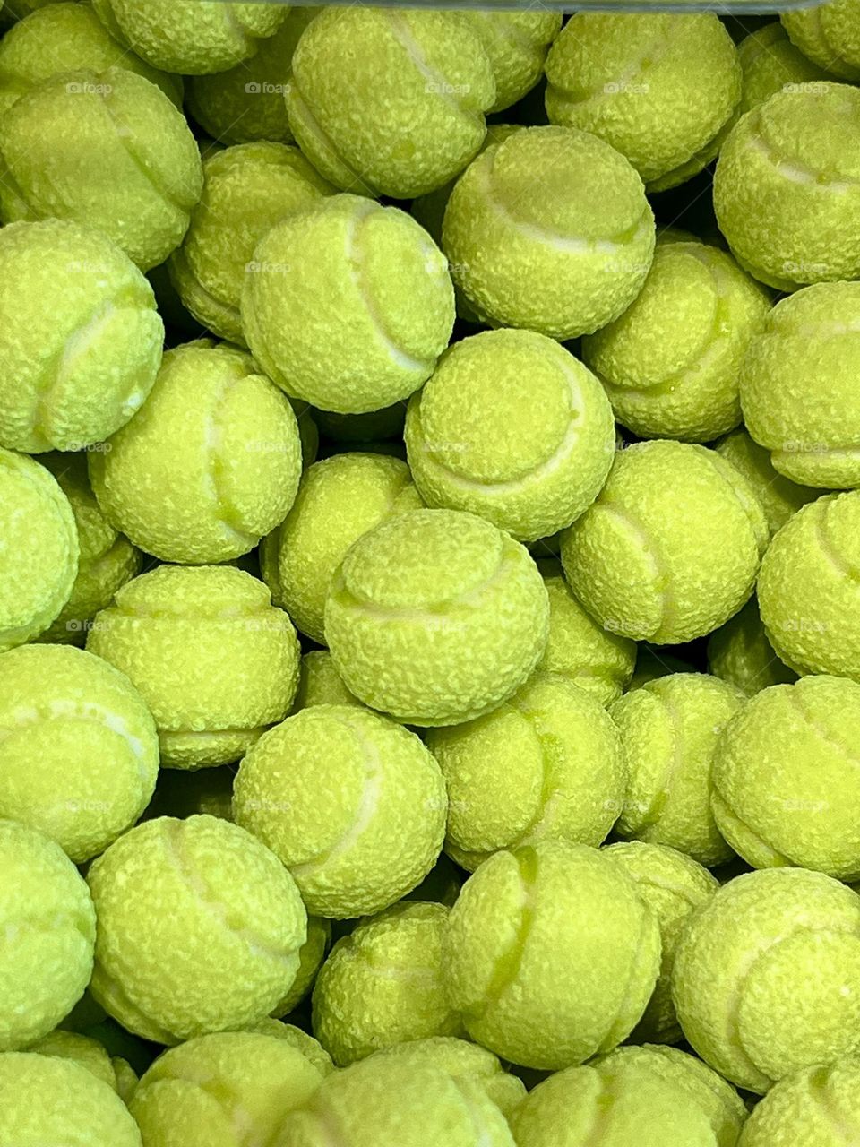 Green candies in the shape of tennis balls with a textured surface that resembles a real tennis ball. The bright color and details create an interesting visual effect.
