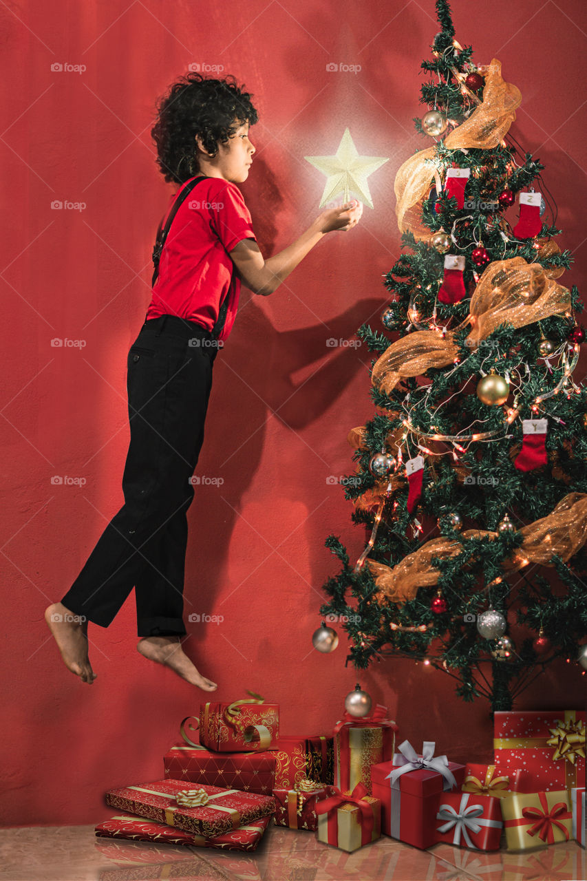 Child putting Christmas tree star, boy's edition floating