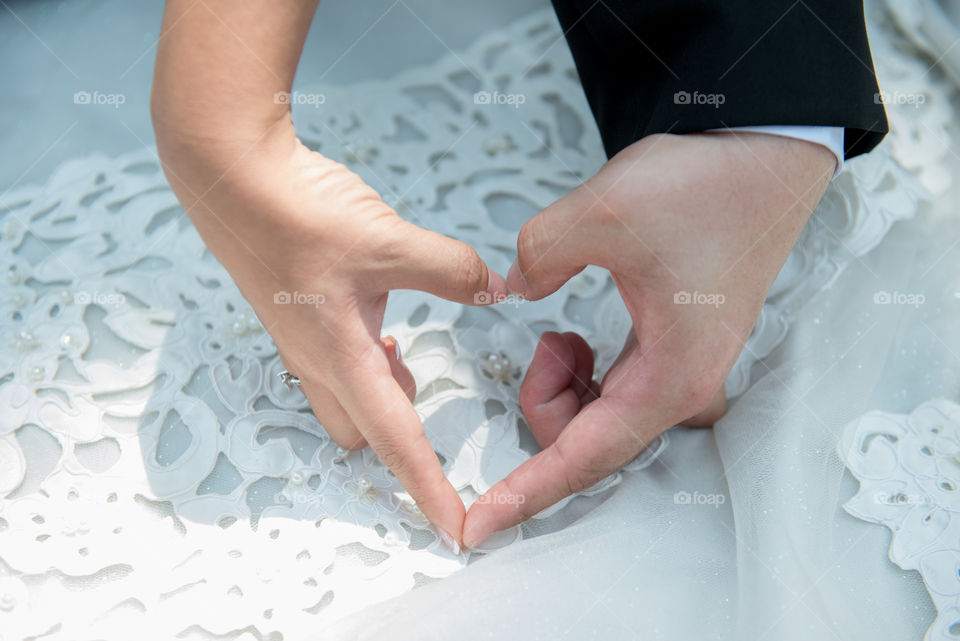 Bride and groom making heart shape