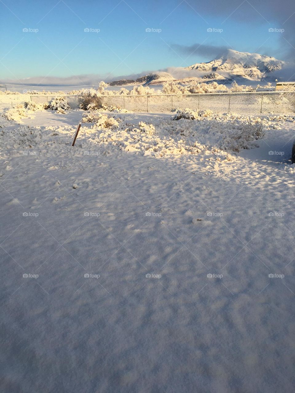 A photo of the ground covered in snow and snow on mountains in the distance. 