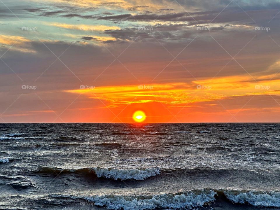 A breathtaking and radiant sunset which colors the waves iridescent, often towers and collides the shore with great force. The impact of the waves against the coastline created a stunning display of energy and motion