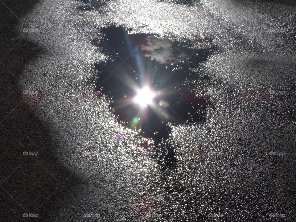 Sonne reflektiert sich in einer Regenpfütze