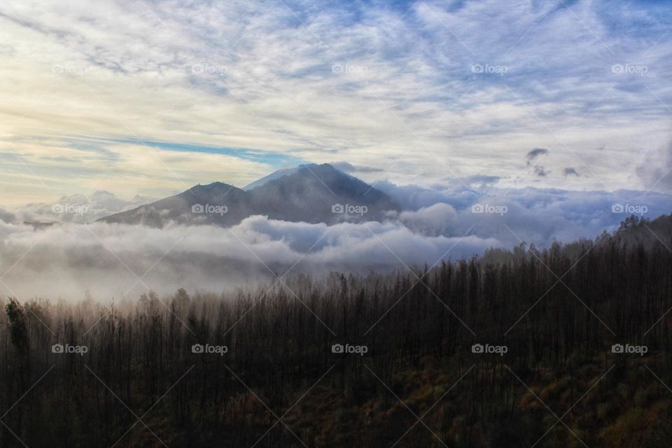 View from Mount Batur after sunrise with mountain peak looking through the fog.