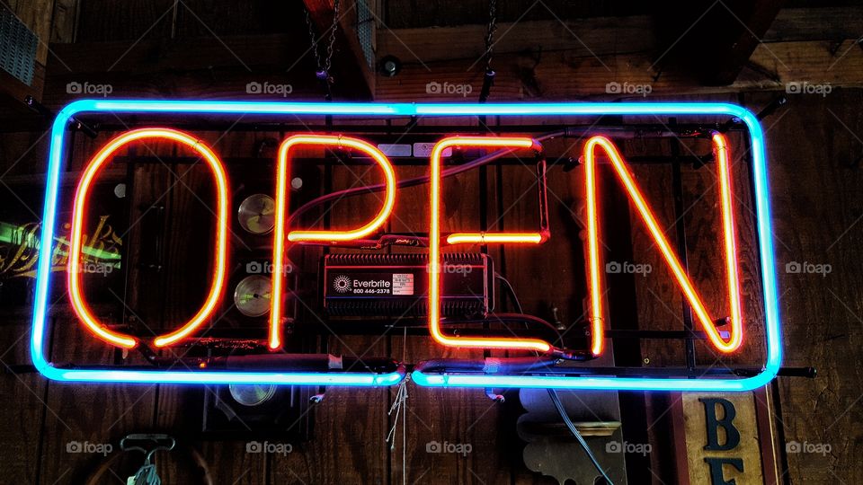 A neon open sign welcoming patrons into its antique shop.