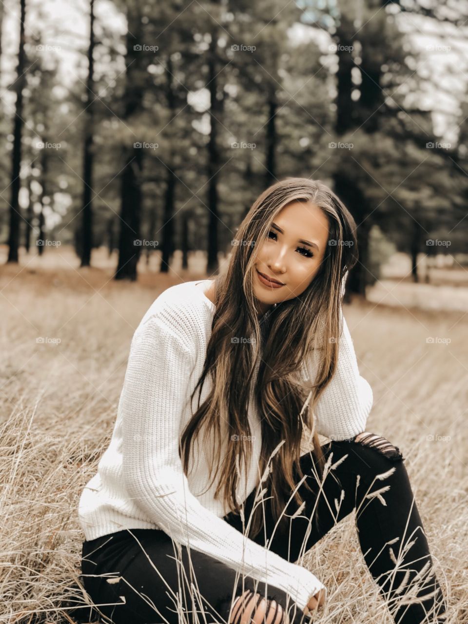 Young girl bundled up in a sweater posing in a field in the mountains.
