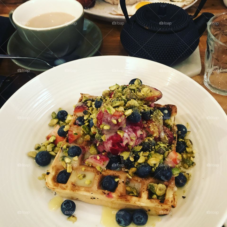 Waffles with berries, white chocolate sauce and pistachio 