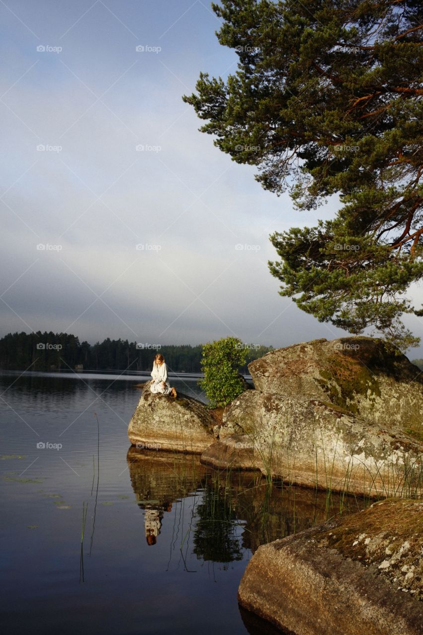 Woman enjoying sunrise in Sweden by a glassy lake