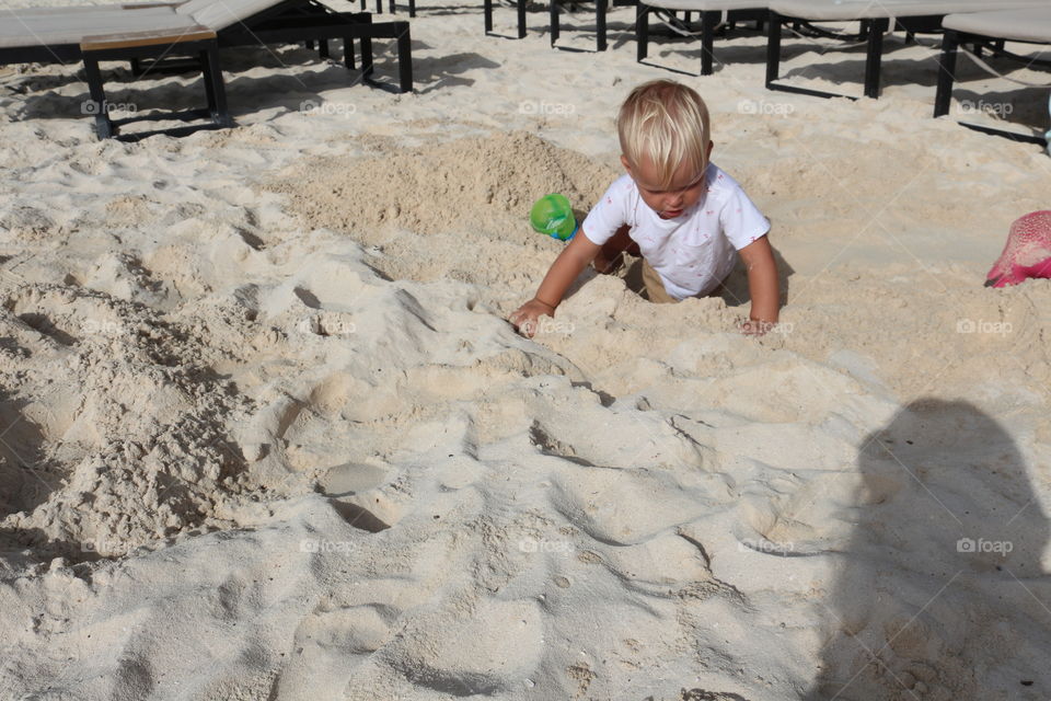 Boy playing with sand at the Caribbean Sea 