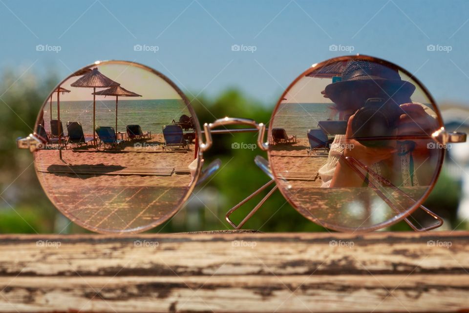 Reflection of the beach, photographer and summer on  mirrored sunglasses