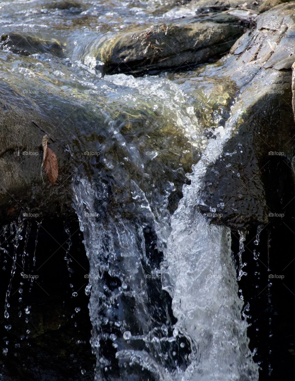 Waterfall frozen in time over green moss.