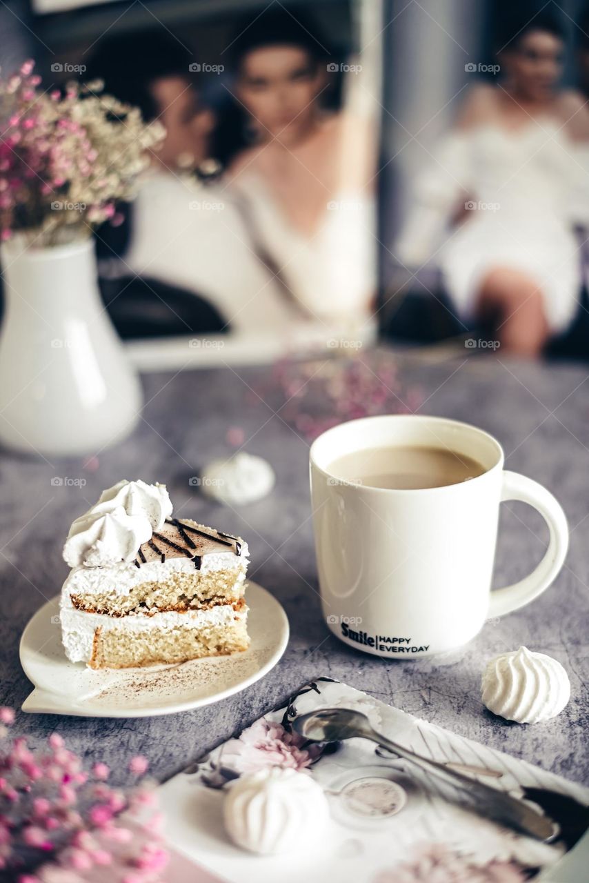 Food still life lifestyle, coffee with milk in a white cup and homemade cake on a light gray background