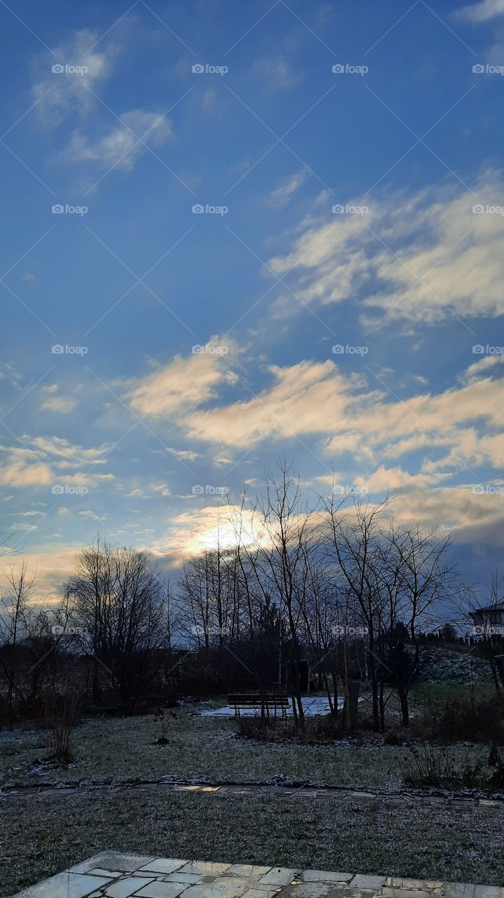 frosty winter morning in blue with sun peeking out from behind the clouds