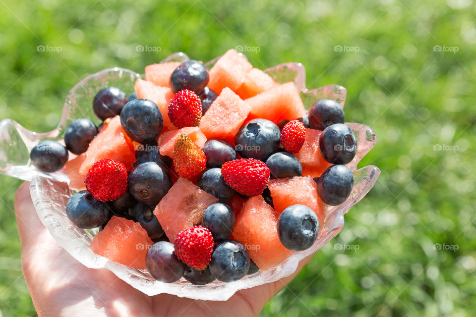 Fresh berries and fruit in a glass bowl in sunny weather 