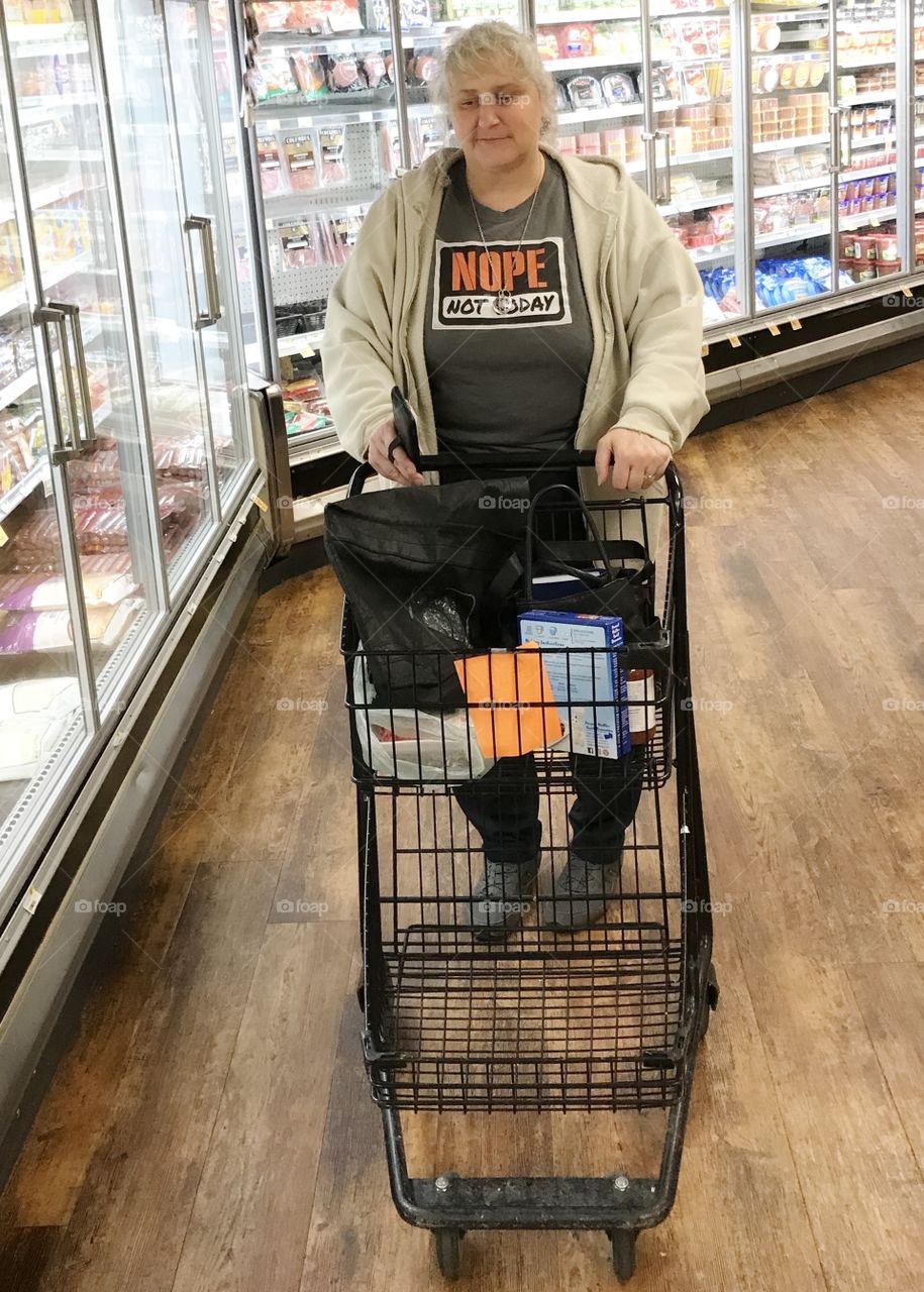 A woman pushes a shopping cart while shopping at the supermarket. 