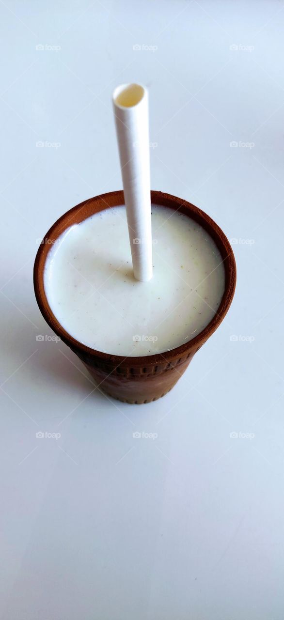 Sweetened curd in circular shape kulhad and circle straw with it.