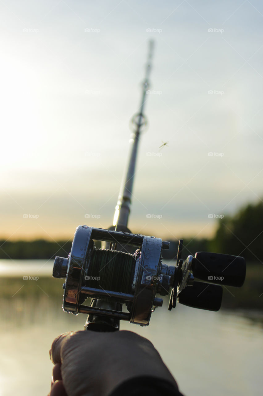 Male hand on a wet round fishing reel