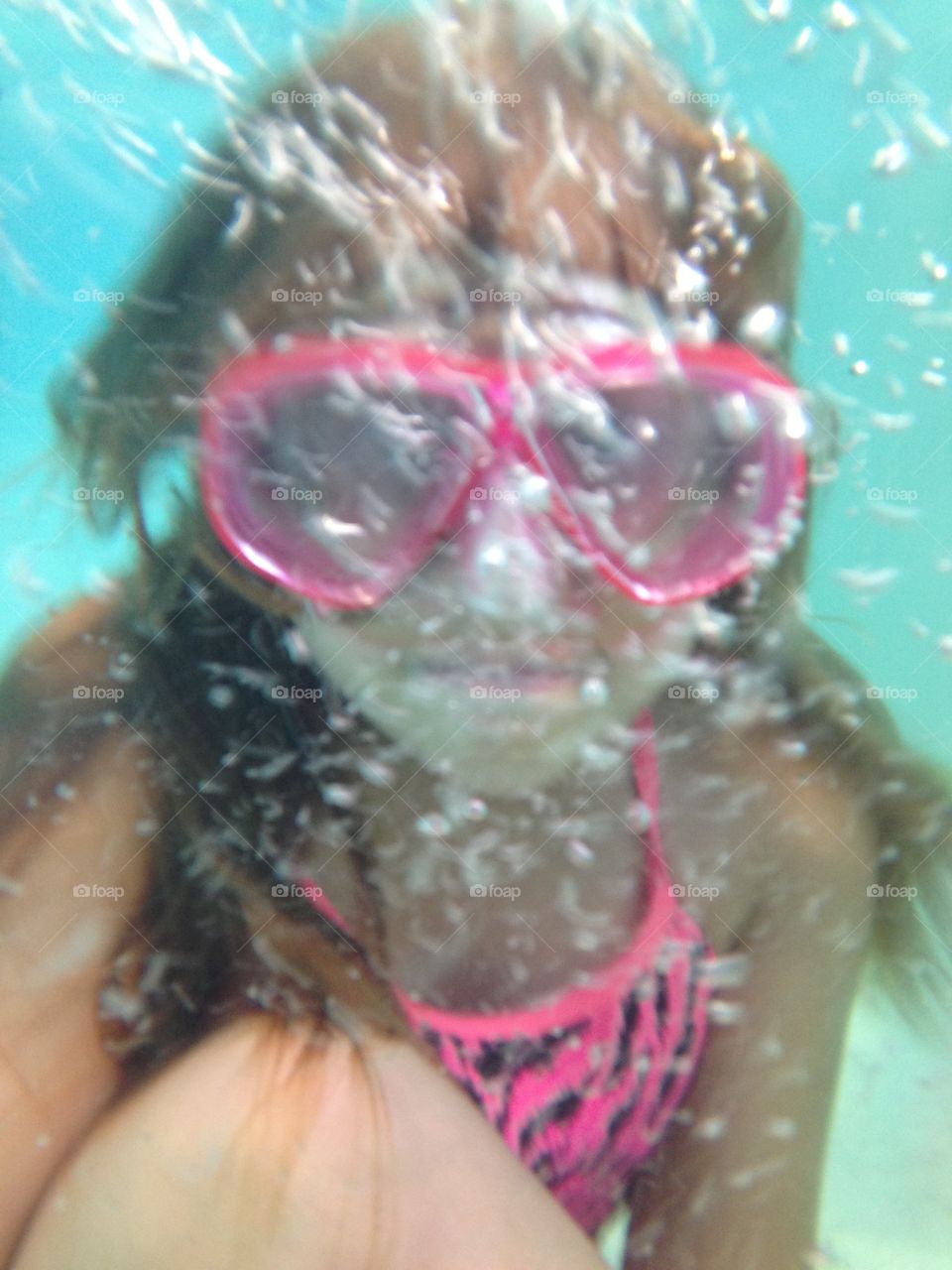 Behind the bubbles. Underwater view of a girl swimming and bubbles in a pool